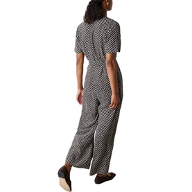 Model wearing Whistles brown geometric print wide-leg jumpsuit with short sleeves and relaxed fit, styled with black flat shoes, rear view.
