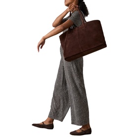 Model carrying Whistles brown suede oversized tote bag, styled with monochrome print wide-leg trousers and flat loafers