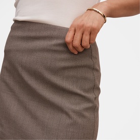 Model wearing Forever New Check Suit skirt in taupe, close-up of hip and pocket detail, styled with a gold chain bracelet.