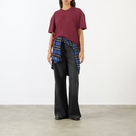 Model wearing Pellador Nutmeg Tonal Logo T-Shirt in maroon, styled with black wide-leg jeans and a blue plaid shirt tied at the waist.