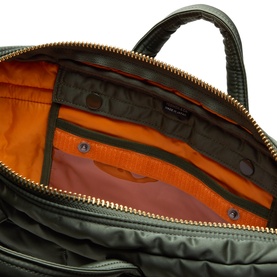 Porter Yoshida sage green nylon briefcase interior showing orange lining, multiple zip pockets, and gold-tone zip fastenings