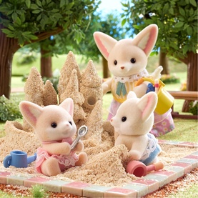 Sylvanian Families fennec fox figures building a sandcastle outdoors, with small beach accessories on a patterned mat