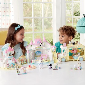 Two children playing with Sylvanian Families multicoloured castle and bus playsets with small animal figures on a bright tabletop