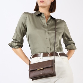 Model carrying Wandler Ida Trio Crossbody Bag in Soil Caviar leather with gold-toned clasp, styled with olive satin shirt and wide belt