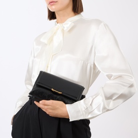Model carrying Wandler Ida Trio Crossbody Bag in Black Glaze leather, gold-toned clasp, styled with cream satin blouse and black trousers