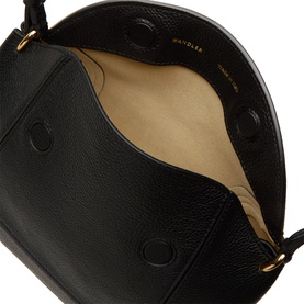 Black leather bag interior view showing beige lining, gold-tone hardware and stud details, with top handle visible above