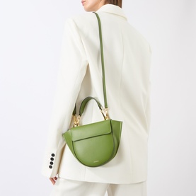 Model carrying Wandler Hortensia Mini Shoulder Bag in Verde green leather, gold-toned hardware, worn cross-body over cream blazer.