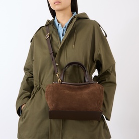 Model carrying Wandler Ida Leather Shoulder Bag in Palissander Suede, structured rectangular shape, double top handles, gold hardware, worn with