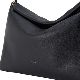 Wandler Black Crust leather tote bag, close-up showing pebbled texture and gold logo lettering with top handle detail.