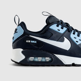Nike Air Max 90 trainer in navy and light blue with white Swoosh, visible Air unit, and white rubber sole