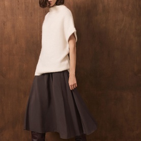 Model wearing Mint Velvet cream oversized knit top with batwing sleeves, styled with a dark grey midi skirt and sheer tights.