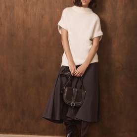 Model wearing Mint Velvet cream knit top with dark grey midi skirt, styled with a dark brown structured shoulder bag.