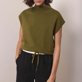 Model wearing Mint Velvet green sleeveless mock-neck knit top with drawstring hem, styled with black wide-leg trousers.