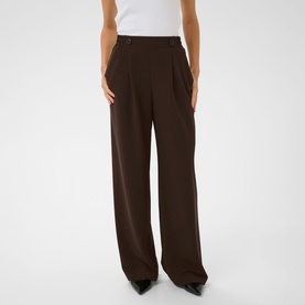 Model wearing Kaffe Phoebe High-Rise Wide Leg Trousers in Coffee Bean, draped wide-leg fit, styled with a white top and black heels.
