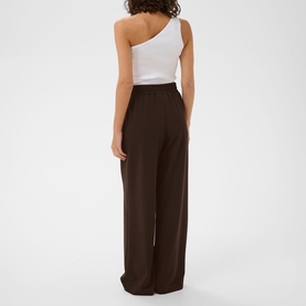 Model wearing Kaffe Phoebe High-Rise Wide Leg Trousers in Coffee Bean, draped wide-leg fit, styled with a white one-shoulder top, rear view.