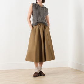 Model wearing Max Mara Studio Gela Zip Knitted Vest in kaki, sleeveless hoodie style, styled with a midi skirt and loafers