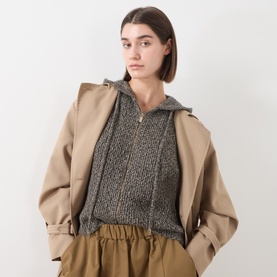 Model wearing Max Mara Studio Gela Zip Knitted Vest in kaki, sleeveless with front zip and hood, styled over a beige trench coat