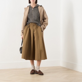 Model wearing Max Mara Studio Gela Zip Knitted Vest in khaki, sleeveless with hood, styled with beige coat, midi skirt and loafers