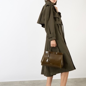 Model carrying Victoria Beckham Sloane Frame Shoulder Bag in dark olive leather, gold-tone hardware, top handle