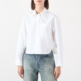 Model wearing Anine Bing white cotton cropped shirt with curved hem and long sleeves, styled with blue denim jeans.