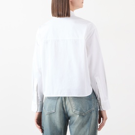 Model wearing Anine Bing white cotton shirt, rear view, with cropped hem and zip cuffs, styled with light blue denim jeans.