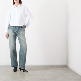 Model wearing Anine Bing white cotton shirt with light wash straight-leg jeans and black heeled ankle boots.