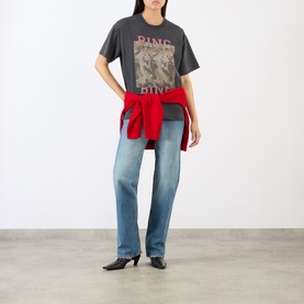 Model wearing Anine Bing black graphic cotton T-shirt, styled with light blue straight-leg jeans and red knitwear tied at waist.