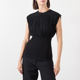 Model wearing Anine Bing black sleeveless top with gathered ruching detail at waist, styled with black tailored trousers.