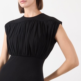 Model wearing Anine Bing black viscose top with ruched bodice, crew neck, and cap sleeves, styled with black trousers.