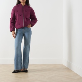 Model wearing Fabienne Chapot Hearty 3D Heart Appliqu&eacute; Bomber Jacket in Brigitte Bordeaux with light-wash wide-leg jeans and black loafers.