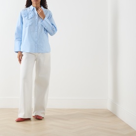 Model wearing Fabienne Chapot Alex 3D Floral Appliqu&eacute; Blouse in Icey Blue with classic collar, wide cuffs, styled with white wide-leg trousers.