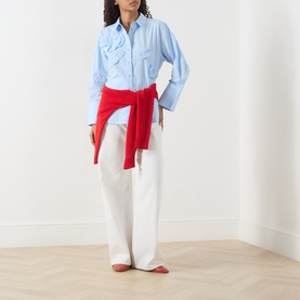 Model wearing Fabienne Chapot Alex 3D Floral Appliqu&eacute; Blouse in Icey Blue with white wide-leg trousers and red flats
