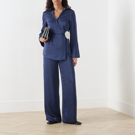 Model wearing Fabienne Chapot Maritime Blue wrap shirt with floral detail, styled with matching wide-leg trousers and carrying a small black clutch