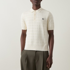 Model wearing cream Fred Perry textured knit polo shirt with zip neck, styled with olive trousers