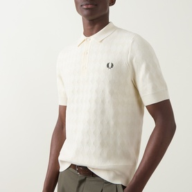 Model wearing cream Fred Perry polo shirt with tonal geometric jacquard pattern and embroidered laurel wreath logo, styled with olive trousers