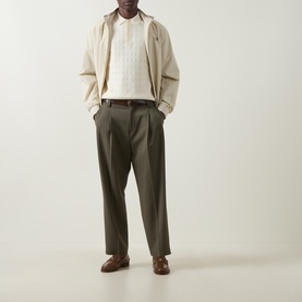Model wearing olive wide-leg tailored trousers, styled with a cream knit polo and beige jacket, brown leather loafers