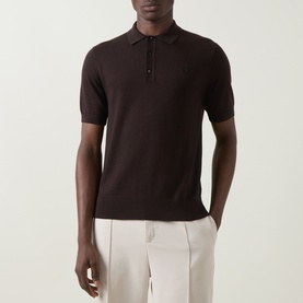 Model wearing Fred Perry Laurel Wreath Logo Polo Shirt in Rich Brown, short-sleeved knit polo with button neck, styled with white trousers