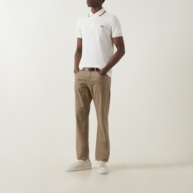 Model wearing Fred Perry Laurel Wreath Logo Twin Tipped Polo Shirt in Ecru with burgundy and green tipping, styled with tan chinos and white trainers.