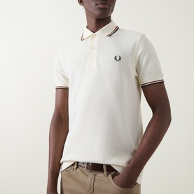 Model wearing Fred Perry Laurel Wreath Logo Twin Tipped Polo Shirt in Ecru with brandy and green tipped collar and cuffs, styled with beige trousers