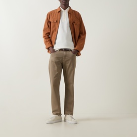 Model wearing Fred Perry Laurel Wreath Logo Twin Tipped Polo Shirt in Ecru, styled with tan overshirt, khaki trousers and white trainers.