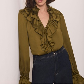 Model wearing Mint Velvet green satin ruffle-trim blouse with V-neckline and elasticated cuffs, styled with dark blue jeans.