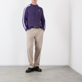 Model wearing Pellador purple ribbed cotton knit with white sleeve stripe detail, styled with beige trousers and black loafers