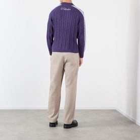 Model wearing Pellador purple cable-knit cotton jumper with white stripe detail, styled with beige trousers and black shoes, rear view