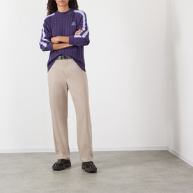 Model wearing Pellador purple cotton ribbed knit jumper with white sleeve stripe detail, styled with beige wide-leg trousers and black loafers