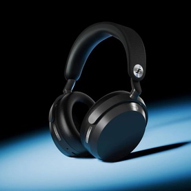 Over-ear wireless headphones in dark navy and black with silver headband detail, shown against a dramatic dark background with blue light