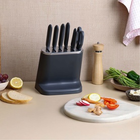 Zyliss grey knife block set with 5 knives, styled on kitchen counter with chopping board, vegetables, and bread nearby