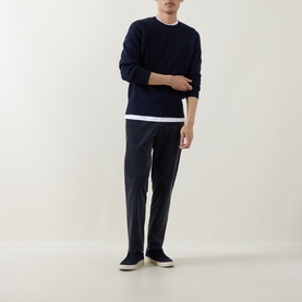 Model wearing Belstaff Bradwell Logo Badge Waffle-Knit Sweater in Dark Ink, styled with white tee, charcoal trousers and dark trainers.