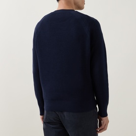 Model wearing Belstaff Bradwell Logo Badge Waffle-Knit Sweater in Dark Ink, showing rear view of crew neck and ribbed hem, styled with dark trousers.