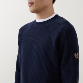 Model wearing Belstaff Bradwell Logo Badge Waffle-Knit Sweater in Dark Ink, crew neck, gold Phoenix badge on sleeve, styled with white tee