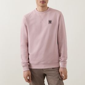 Model wearing Belstaff Logo Badge Sweatshirt in Dusk Pink with crew neck, chest Phoenix logo badge, paired with khaki cargo trousers.